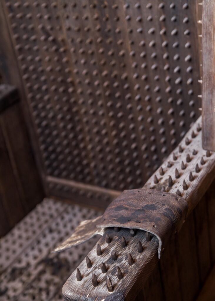 a medieval torture device known as the "Iron Chair," featuring numerous spikes on its seat, backrest, and armrests, designed to inflict severe pain and discomfort on the victim.