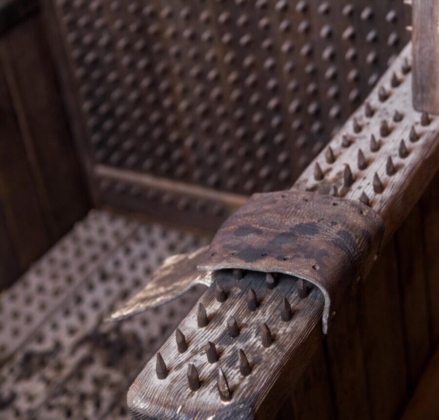 a medieval torture device known as the "Iron Chair," featuring numerous spikes on its seat, backrest, and armrests, designed to inflict severe pain and discomfort on the victim.