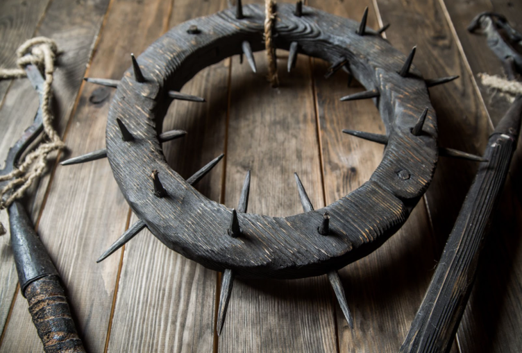 a circular medieval torture device with sharp spikes on its surface, likely used for punishment or interrogation.