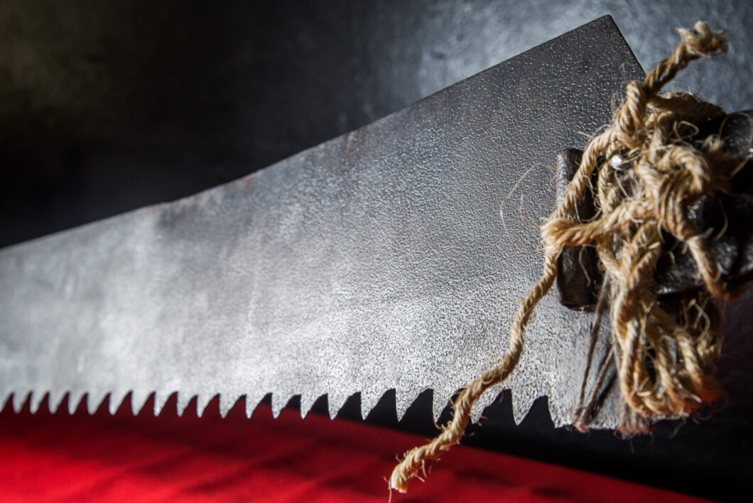 a close-up view of a large, serrated metal saw blade tied with rough rope at one end