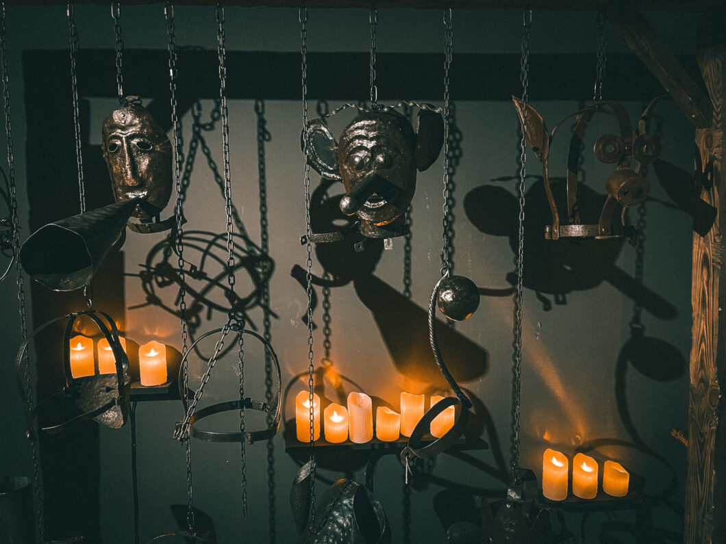 a dimly lit medieval-themed display featuring metal masks, chains, and various iron objects