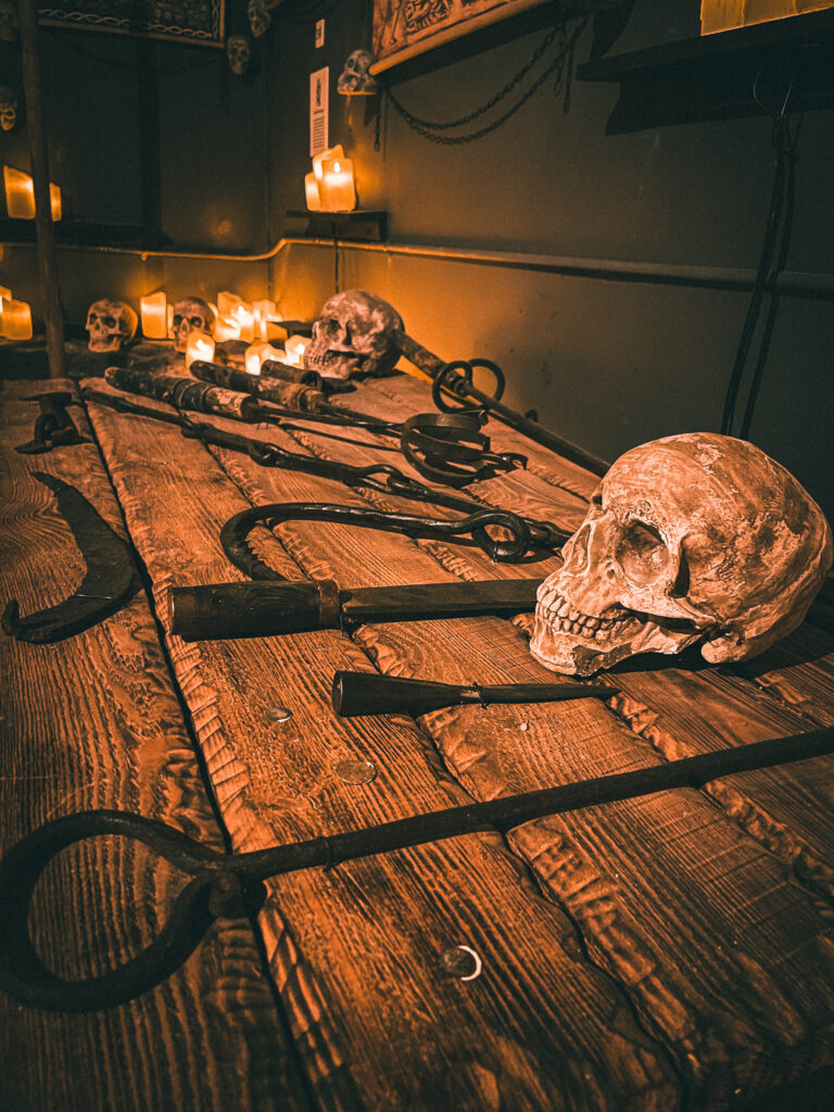 a rustic wooden table displaying various medieval torture devices, including hooks, clamps, and restraints