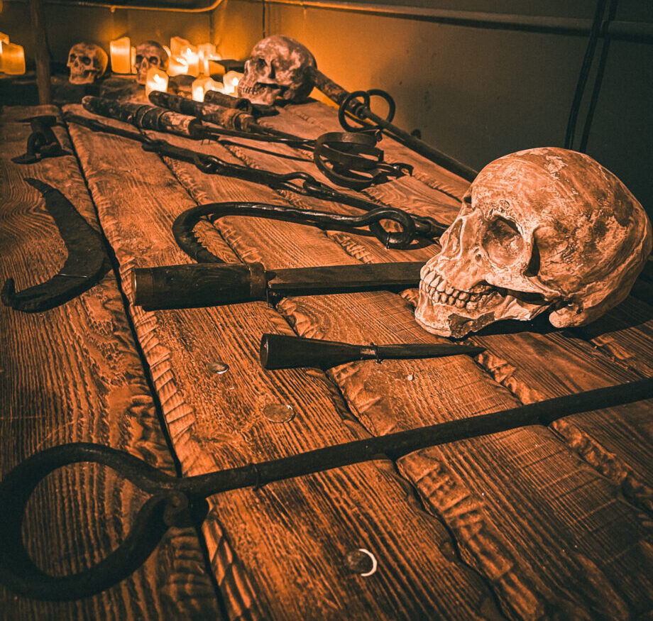 a rustic wooden table displaying various medieval torture devices, including hooks, clamps, and restraints