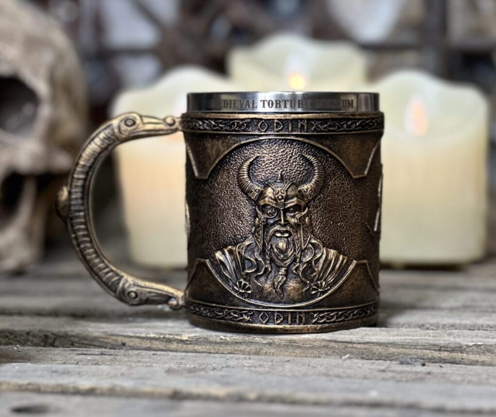 a detailed, bronze-colored mug with a Viking-themed design, featuring a depiction of Odin with horns on the front