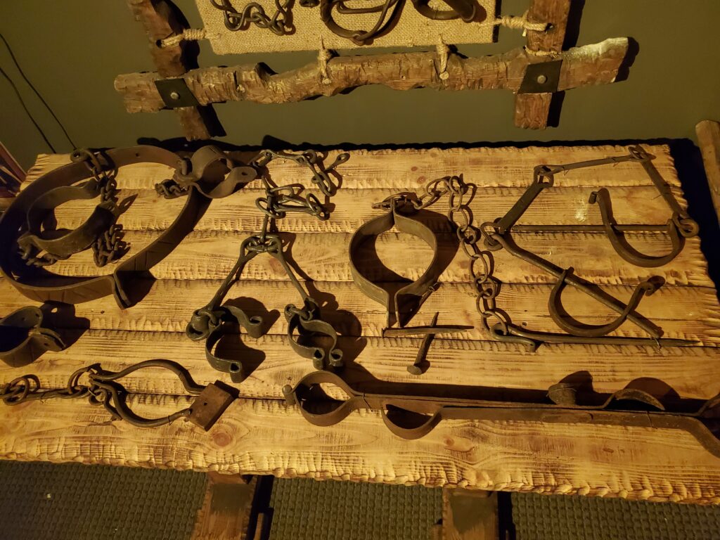 a collection of iron restraints and shackles displayed on a wooden surface