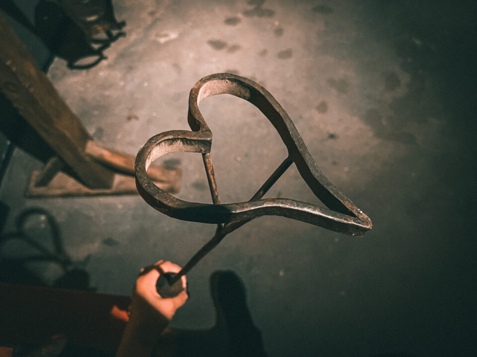 a metal branding iron in the shape of a heart, held by a person